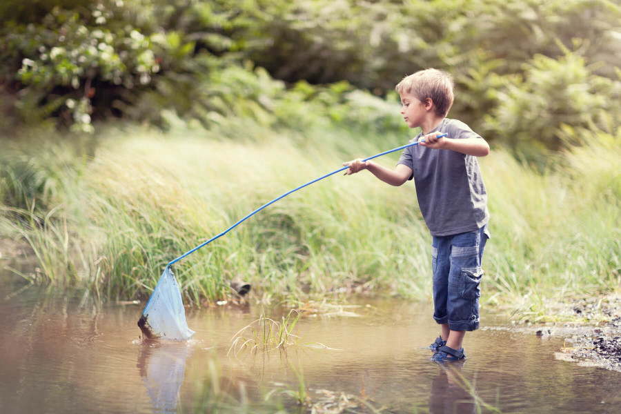 child playing with a net in a river